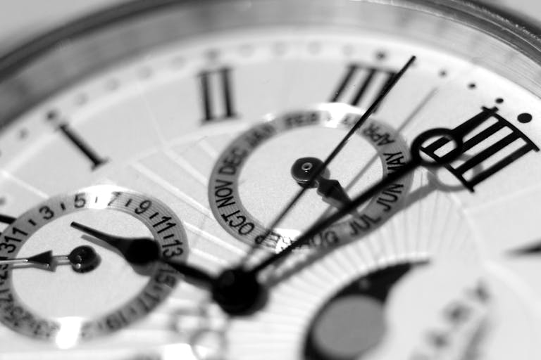 Detailed black and white shot of an elegant watch face showcasing timekeeping elements.